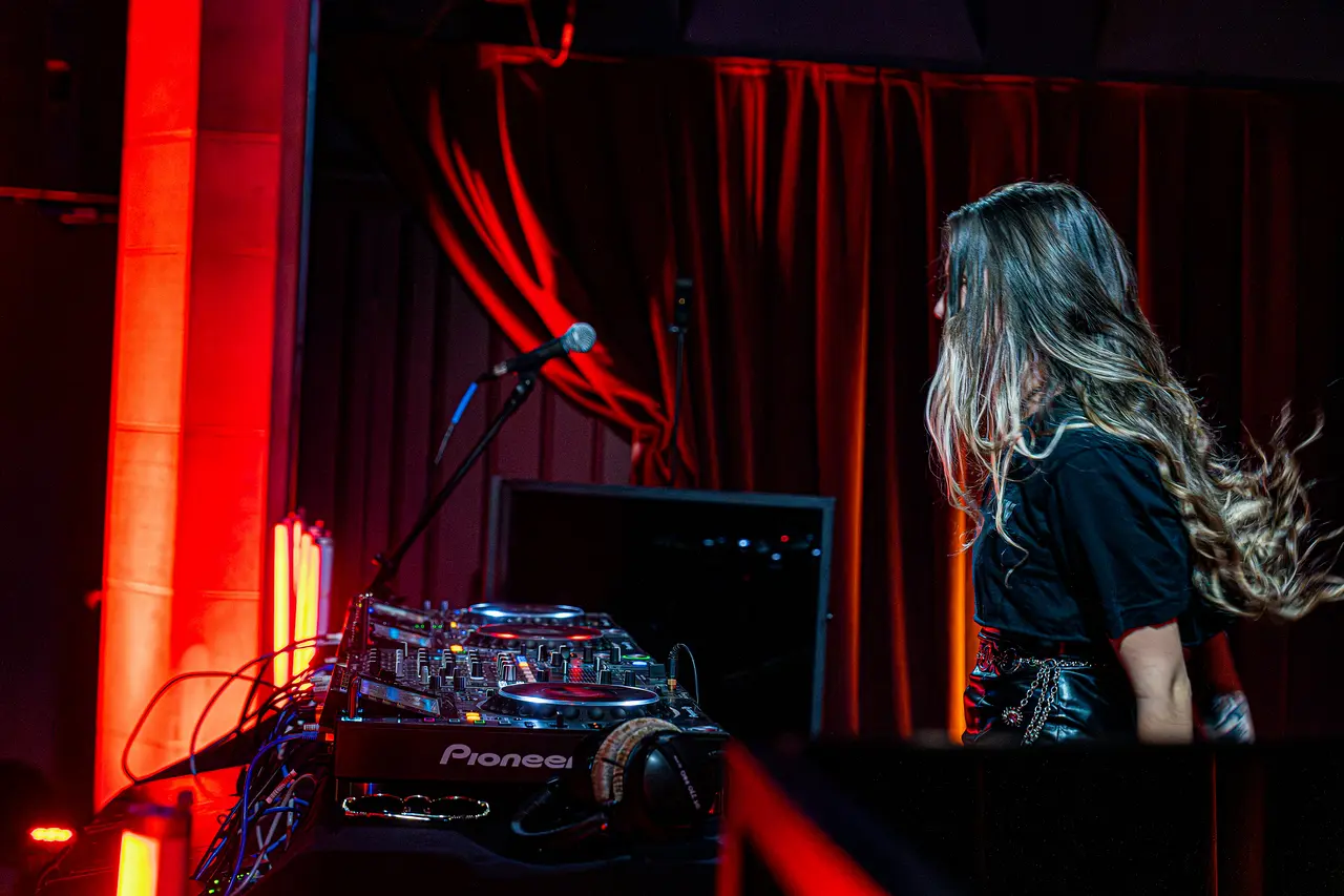 DJ performing under red club lighting
